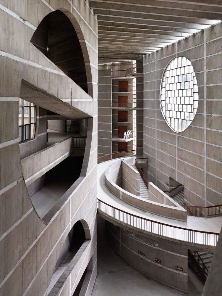 Interior ramps and concrete geometry inside the National Parliament House, showing curved walkways and circular windows in Dhaka.