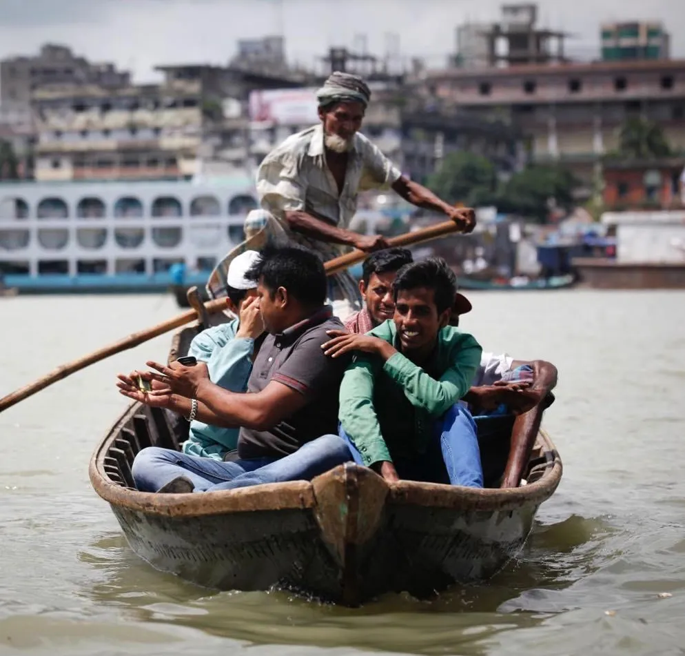 Passengers travelling by traditional wooden boat on the Buriganga River in Dhaka, Bangladesh.