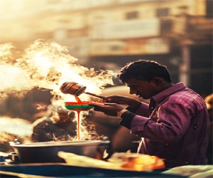 A street tea vendor in Dhaka pours hot tea amid rising steam on a busy day in the city.