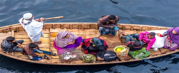 People travelling in a traditional wooden boat on Dhaka's river, photographed from above, showing daily river life and local culture.
