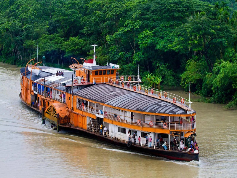 Traditional river cruise paddle steamer sailing through lush green waterways in Barisal, Bangladesh.